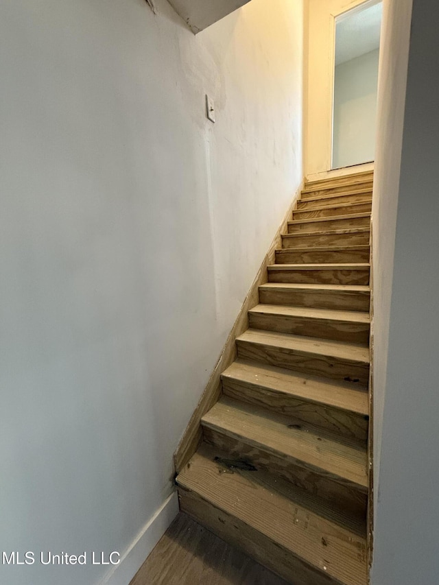 staircase featuring baseboards and wood finished floors