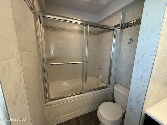 bathroom with enclosed tub / shower combo, wood-type flooring, toilet, and tile walls