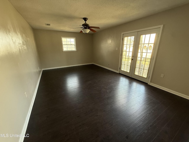 empty room with ceiling fan, dark hardwood / wood-style floors, a textured ceiling, and french doors