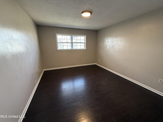 empty room featuring dark hardwood / wood-style floors and a textured ceiling