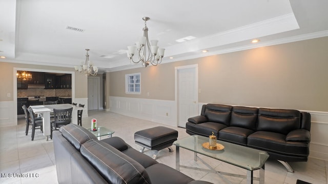 tiled living room with a notable chandelier, ornamental molding, and a raised ceiling