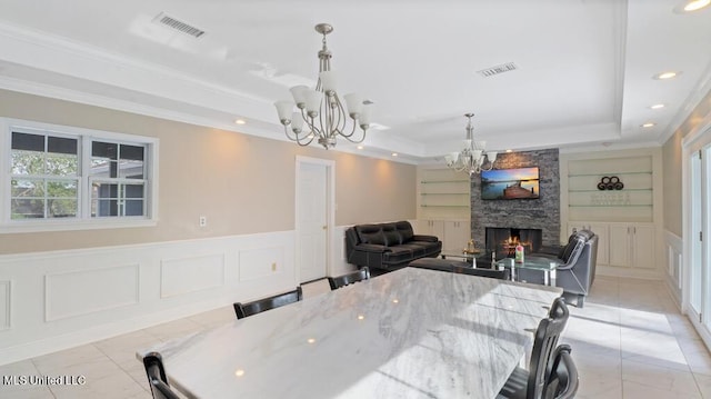 dining room featuring visible vents, a notable chandelier, a raised ceiling, and a decorative wall