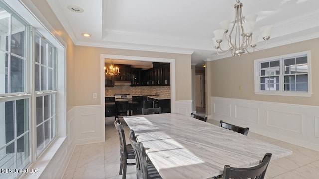 dining room with an inviting chandelier, sink, crown molding, and a raised ceiling