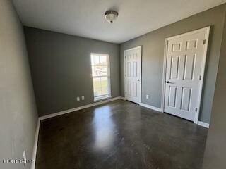 unfurnished bedroom featuring baseboards, concrete floors, and multiple closets