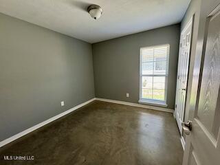 unfurnished bedroom with baseboards and concrete floors