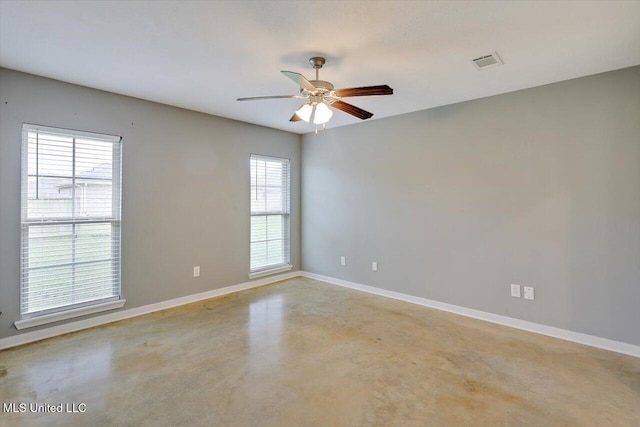 spare room featuring concrete flooring, plenty of natural light, baseboards, and ceiling fan