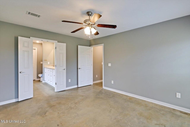 unfurnished bedroom with baseboards, concrete floors, ensuite bathroom, and a ceiling fan