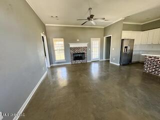 unfurnished living room with a ceiling fan, baseboards, a fireplace, concrete flooring, and ornamental molding