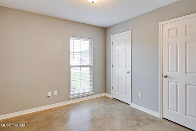 unfurnished bedroom with finished concrete floors and baseboards