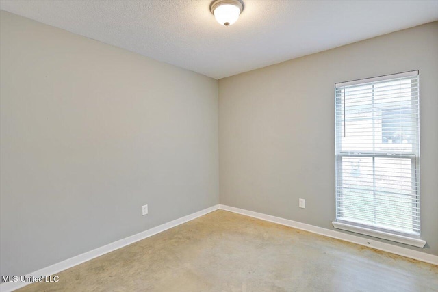 empty room with baseboards and a textured ceiling