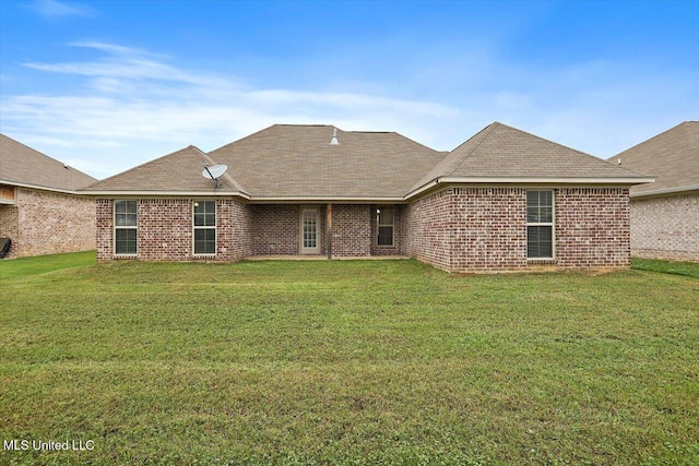 back of house featuring a yard, brick siding, and a shingled roof