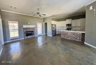 unfurnished living room with ceiling fan, baseboards, ornamental molding, concrete flooring, and a fireplace