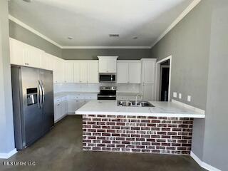 kitchen featuring stainless steel appliances, a sink, a peninsula, light countertops, and white cabinetry