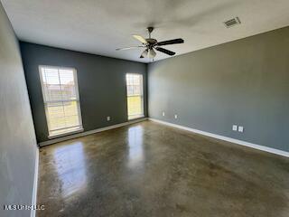 unfurnished room featuring concrete flooring, baseboards, and ceiling fan