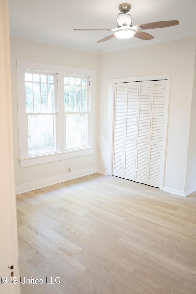unfurnished bedroom with wood finished floors, a closet, baseboards, and a ceiling fan