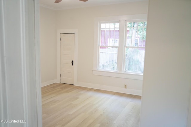 empty room featuring light wood-style floors, a ceiling fan, ornamental molding, and baseboards