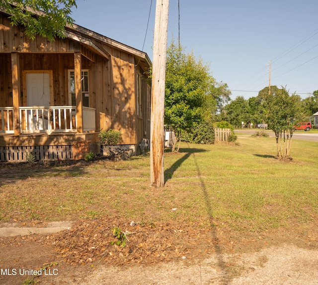 view of green lawn featuring covered porch