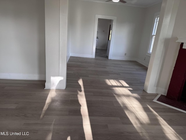unfurnished dining area with ornamental molding, ceiling fan, baseboards, and wood finished floors