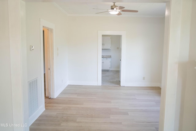 unfurnished room with a ceiling fan, light wood-style floors, crown molding, and baseboards