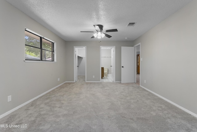 449 Klondyke Rd, Long Beach, MS 39560 - unfurnished bedroom featuring a walk in closet, a textured ceiling, light colored carpet, and baseboards