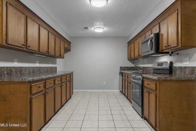 449 Klondyke Rd, Long Beach, MS 39560 - kitchen featuring a textured ceiling, baseboards, dark countertops, and appliances with stainless steel finishes