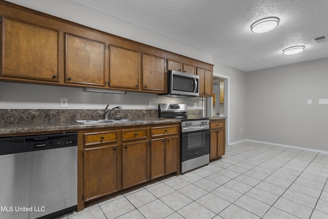 449 Klondyke Rd, Long Beach, MS 39560 - kitchen featuring brown cabinets, a sink, dark countertops, stainless steel appliances, and a textured ceiling