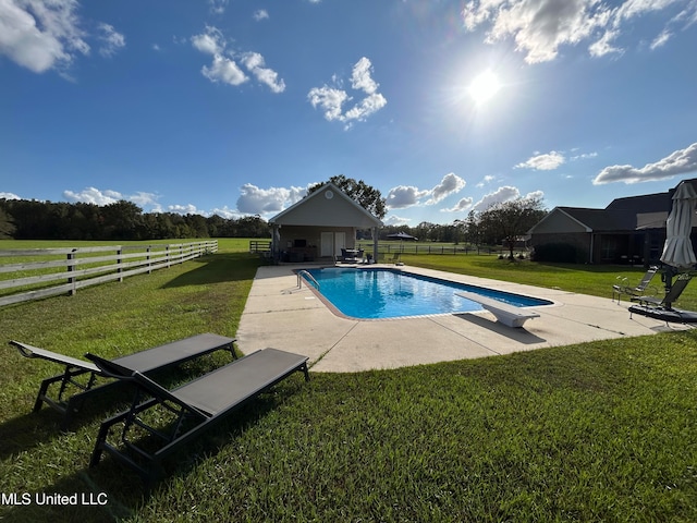 view of pool featuring a diving board, a rural view, a lawn, and a patio