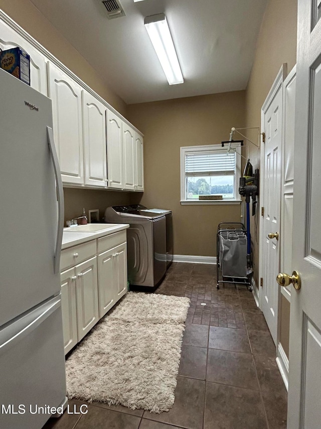 laundry room featuring cabinets, washing machine and dryer, and dark tile patterned flooring