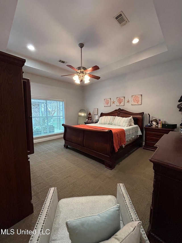 carpeted bedroom featuring ceiling fan and a raised ceiling