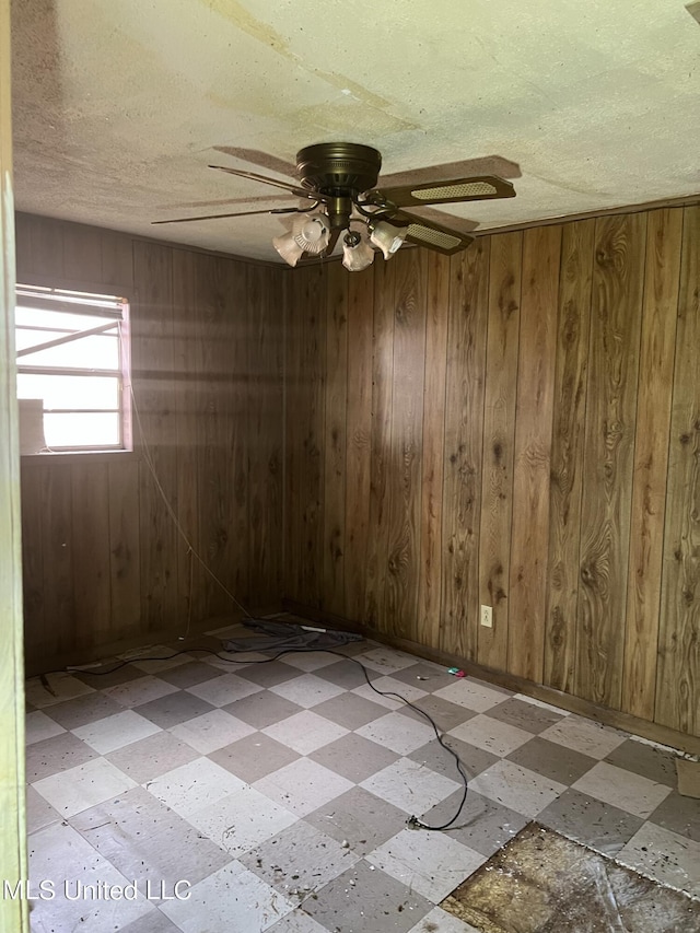 514 Lincoln Ave, Indianola, MS 38751 - spare room with tile patterned floors, wooden walls, ceiling fan, a textured ceiling, and baseboards