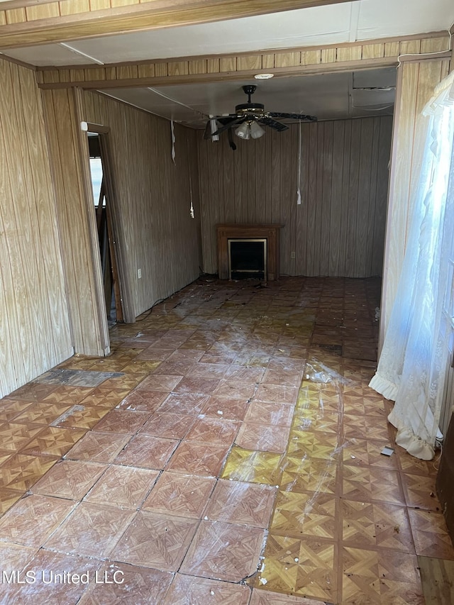 514 Lincoln Ave, Indianola, MS 38751 - unfurnished living room featuring wood walls, a ceiling fan, and a fireplace