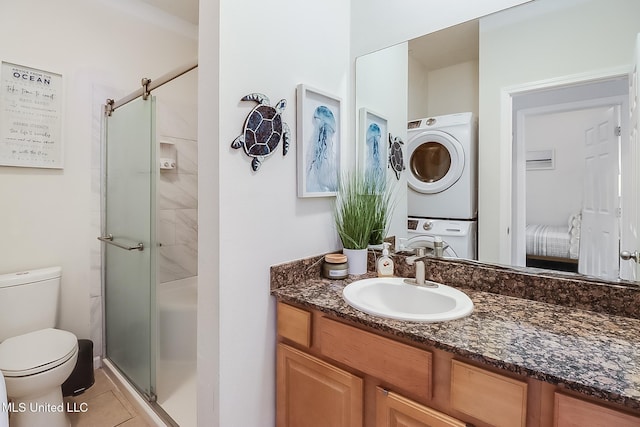 bathroom featuring vanity, stacked washer / drying machine, a shower with shower door, tile patterned floors, and toilet