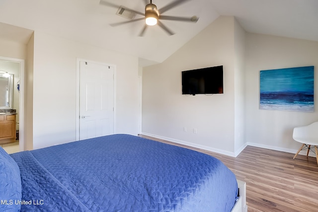 bedroom with ceiling fan, wood-type flooring, connected bathroom, and vaulted ceiling