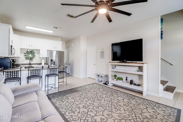 living room featuring ceiling fan, sink, and light tile patterned floors