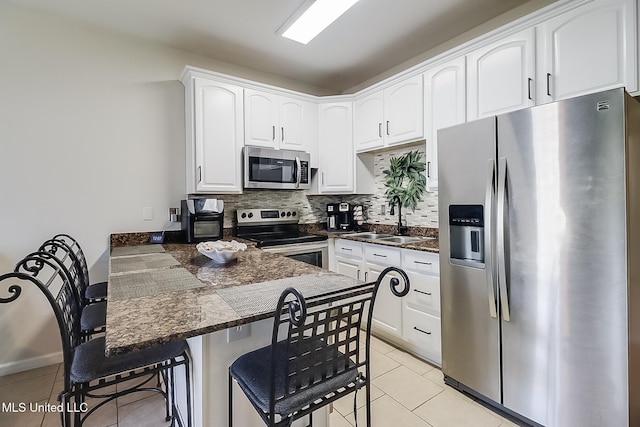 kitchen featuring sink, appliances with stainless steel finishes, a kitchen breakfast bar, kitchen peninsula, and white cabinets