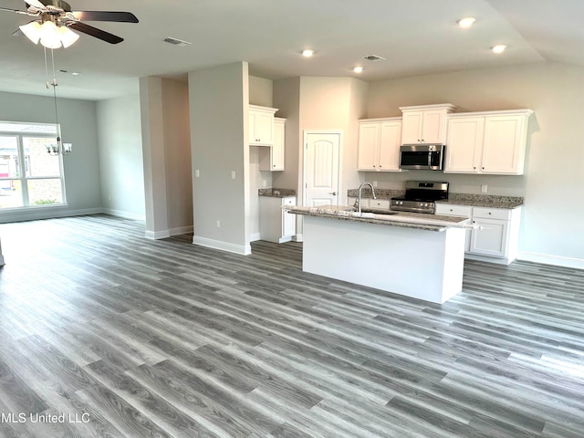 kitchen featuring white cabinets, an island with sink, appliances with stainless steel finishes, and hardwood / wood-style floors