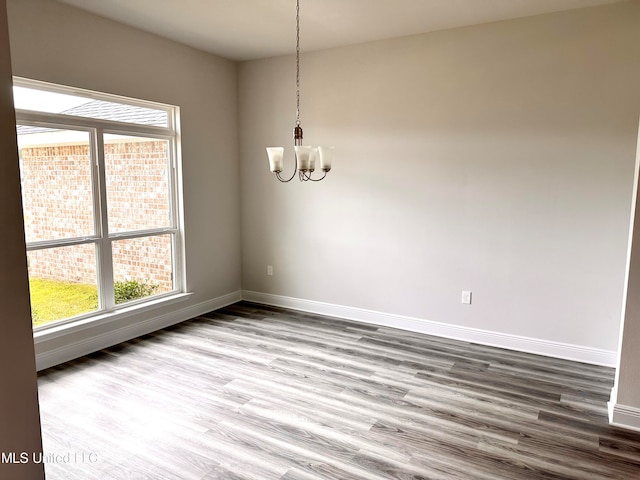 unfurnished dining area featuring hardwood / wood-style flooring and an inviting chandelier