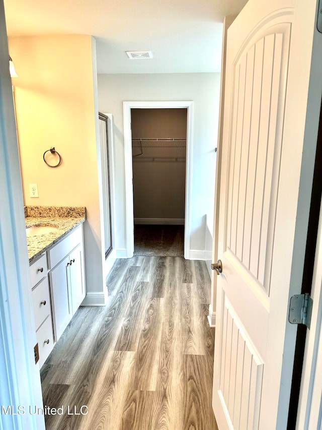 bathroom featuring wood-type flooring, vanity, and walk in shower