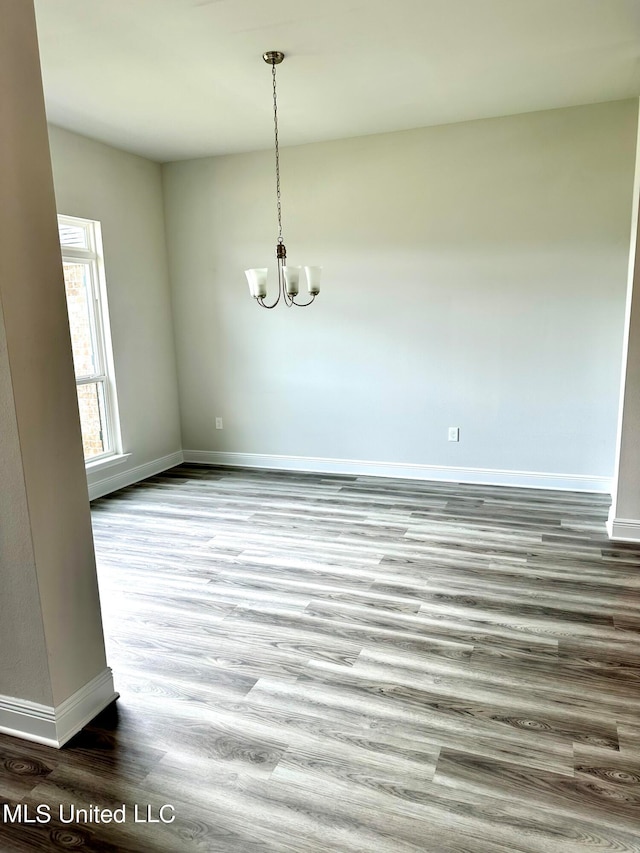 unfurnished dining area featuring a chandelier and wood-type flooring