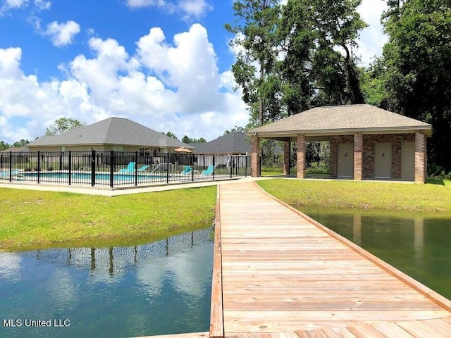 view of dock featuring a fenced in pool, a lawn, and a water view