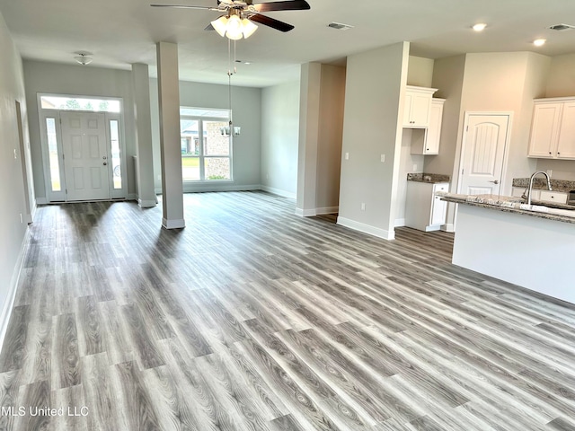 unfurnished living room with ceiling fan with notable chandelier, light wood-type flooring, and sink