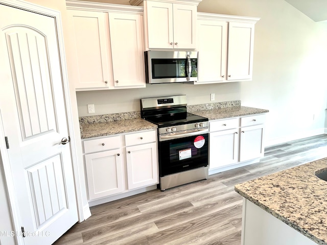 kitchen featuring white cabinets, appliances with stainless steel finishes, light hardwood / wood-style flooring, and light stone countertops