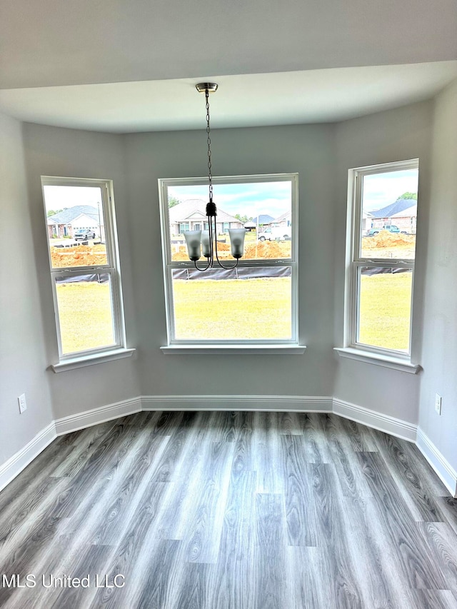 unfurnished dining area featuring hardwood / wood-style flooring and an inviting chandelier