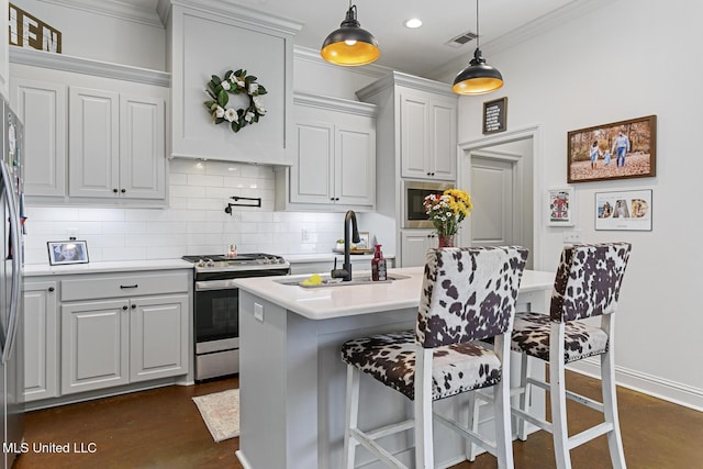 kitchen with sink, a breakfast bar, appliances with stainless steel finishes, white cabinetry, and hanging light fixtures