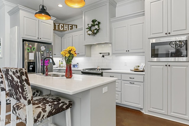 kitchen with sink, a breakfast bar area, white cabinetry, hanging light fixtures, and stainless steel appliances