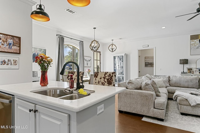 kitchen featuring sink, ornamental molding, white cabinets, a center island with sink, and stainless steel dishwasher