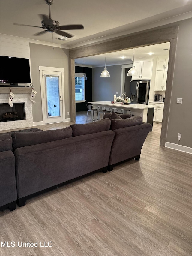 living room with sink, light hardwood / wood-style floors, and ceiling fan