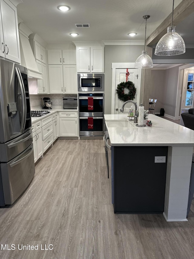 kitchen with pendant lighting, white cabinetry, light wood-type flooring, and appliances with stainless steel finishes