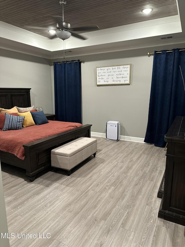 bedroom with wood ceiling, light hardwood / wood-style floors, and a tray ceiling