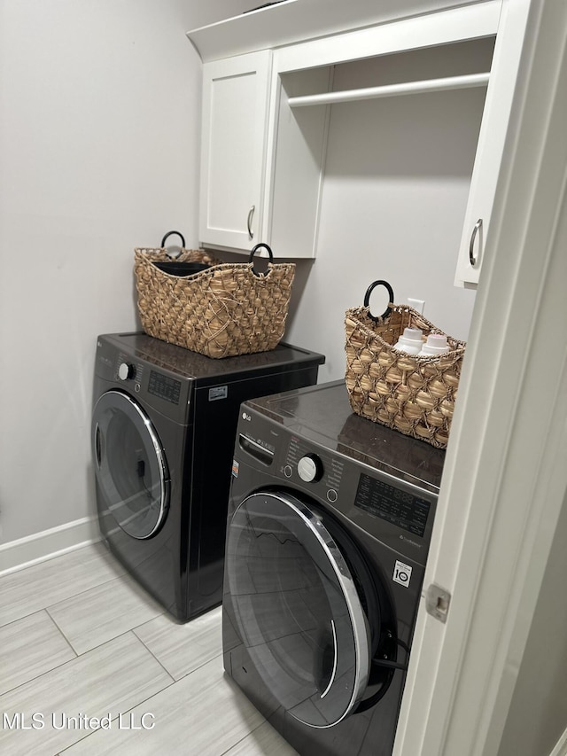 clothes washing area with cabinets and washer and dryer